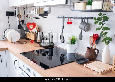 L'intérieur de la cuisine de la maison est décoré de coeurs rouges pour la Saint-Valentin. Décoration sur la table, cuisinière, ustensiles, Banque D'Images