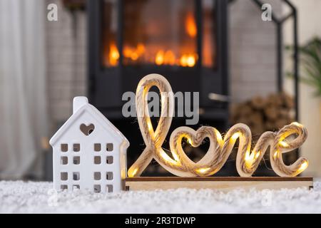 Clé à la maison avec porte-clés contre le fond de la cheminée poêle avec feu et bois de chauffage dans le décor de la Saint-Valentin, l'amour maison. Déplacement vers Banque D'Images