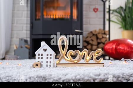 Clé à la maison avec porte-clés contre le fond de la cheminée poêle avec feu et bois de chauffage dans le décor de la Saint-Valentin, l'amour maison. Déplacement vers Banque D'Images