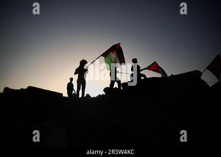 Gaza, Palestine. 24th mai 2023. Des enfants palestiniens élèvent le drapeau de la Palestine sur les ruines de leur maison détruite à la suite de raids israéliens sur la ville de Beit Lahiya, dans le nord de la bande de Gaza. Israël et le Jihad islamique ont accepté une trêve négociée par l'Égypte en retard sur 13 mai. Israël a mené plusieurs attaques contre les dirigeants militaires du Jihad islamique palestinien. Bande de Gaza, 24 mai 2023. Photo de Habboub Ramez/ABACAPRESS.COM crédit: Abaca Press/Alay Live News Banque D'Images