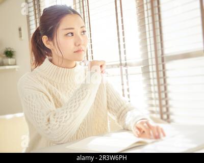 Femme asiatique ouvrant des notes et pensant Banque D'Images