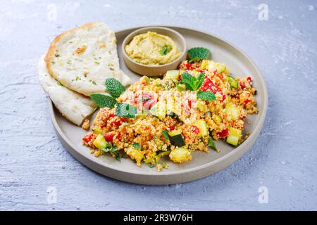 Couscous de légumes marocain traditionnel avec pain pita et houmous servi comme gros plan sur une assiette de Nordic Design Banque D'Images