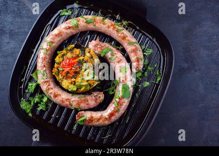 Saucisse italienne traditionnelle de salasiccia, servie avec tartre aux légumes et coriandre comme vue de dessus dans un pa en fonte Banque D'Images