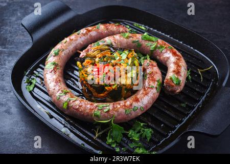 Saucisse italienne traditionnelle salsiccia à la fresque, servie avec tartre aux légumes et coriandre dans un pa en fonte Banque D'Images