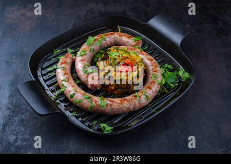 Saucisse italienne traditionnelle salsiccia à la fresque, servie avec tartre aux légumes et coriandre dans une casserole en fonte Banque D'Images