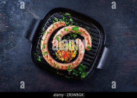 Saucisse italienne traditionnelle de salasiccia, servie avec tartre aux légumes et coriandre comme vue de dessus dans un pa en fonte Banque D'Images