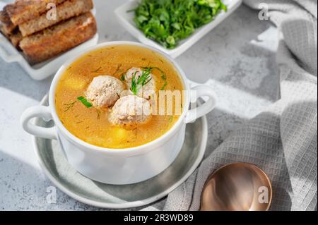 Soupe de légumes avec boulettes de viande dans une tasse de soupe blanche. Soupe pauvre en calories aux herbes et craquelins. Banque D'Images