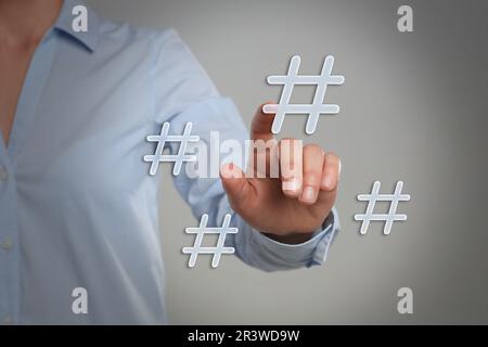 Concept hashtag. Femme pointant vers un panneau sur fond gris clair, gros plan Banque D'Images