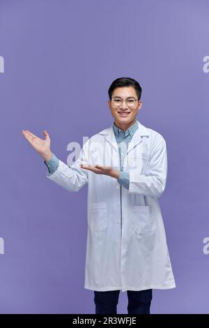 jeune homme souriant médecin montrant et présentant quelque chose avec la main Banque D'Images