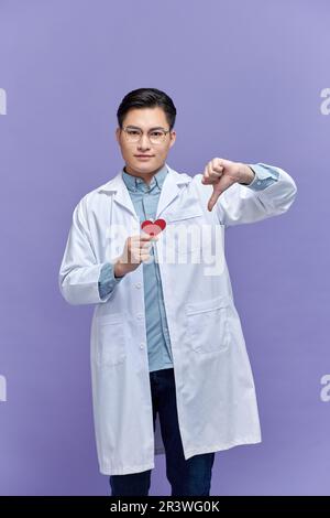cardiologue médecin femme tenant le cœur rouge, signe négatif montrant n'aime pas avec les pouces vers le bas, concept de rejet Banque D'Images
