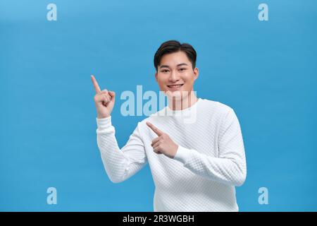 Mouvement jeune homme pointe le doigt sur l'espace de copie portrait sur fond bleu Banque D'Images