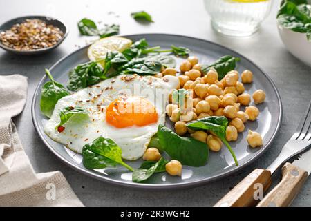 Un petit-déjeuner sain est servi avec des œufs, des pois chiches bouillis et des épinards frais Banque D'Images