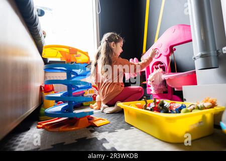 Jeune fille dans un centre de garde de jour jouant avec des jouets de poupées. Banque D'Images