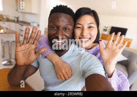 Heureux couple divers ayant des appels vidéo et de passer à la caméra Banque D'Images