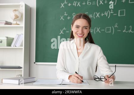 Un jeune professeur de mathématiques donne une leçon à table en classe Banque D'Images