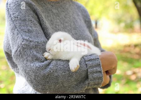 Femme tenant un joli lapin blanc dans le parc, en gros plan Banque D'Images
