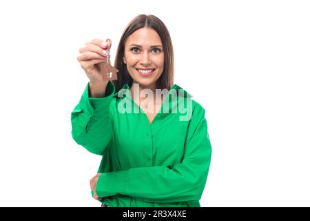 portrait d'une jolie petite femme brune aux yeux bruns vêtue d'une chemise verte qui a reçu les clés de l'appartement Banque D'Images