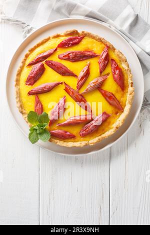 Gâteau maison avec crème anglaise et rhubarbe dans une assiette sur la table. Vue verticale du dessus Banque D'Images