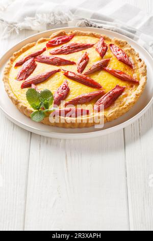 Gâteau maison avec crème anglaise et rhubarbe dans une assiette sur la table. Verticale Banque D'Images