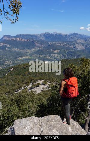 Femme avec sac à dos bénéficiant de la vue sur les montagnes tramuntana et l'ermitage de Maristela, son Ferra, Esporles, Iles Baléares, Espagne. Banque D'Images