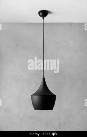 Style loft moderne, chandelier de plafond en métal noir contre un mur en plâtre gris décoratif. Lampe design noire sur fond texturé gris. Banque D'Images