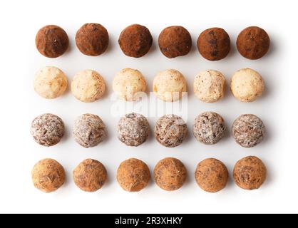 Différents types de truffes au chocolat sur fond blanc vue de dessus. Bonbons ronds faits de lait, chocolat noir et blanc sur isolation. Banque D'Images