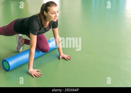 Femme attrayante rouleau mousse faisant de l'exercice et de poser dans un centre de remise en forme moderne Banque D'Images