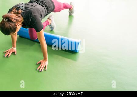 Belle femme l'exercice de remise en forme pilates rouleau mousse faisant de l'exercice et de poser dans un centre de remise en forme moderne Banque D'Images