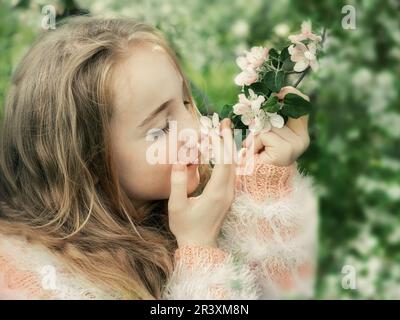 une belle fille de 13-15 ans sourit dans le jardin de printemps, luttant avec la dépression de printemps et appréciant les fleurs. Une fille heureuse avec magnifique wh Banque D'Images