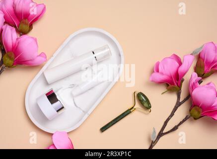 Baignoire en plastique blanc, pot sur un support en marbre et bouquet de magnolia rose, vue du dessus. Banque D'Images