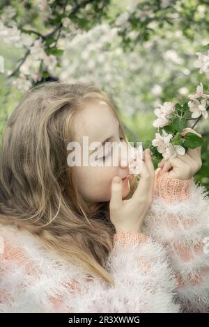 une belle fille de 13-15 ans sourit dans le jardin de printemps, luttant avec la dépression de printemps et appréciant les fleurs. Une fille heureuse avec magnifique wh Banque D'Images