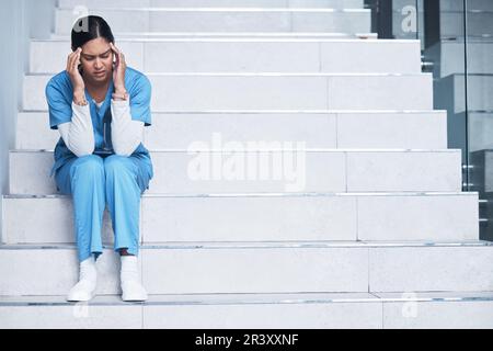 Stress, maux de tête et fatigue avec une infirmière à l'hôpital pour l'épuisement, la santé mentale et la fatigue. Médecine, soins de santé et médecine avec la femme sur les escaliers Banque D'Images