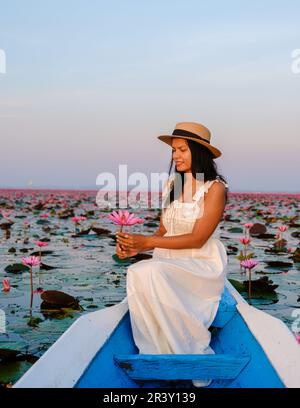 Femmes asiatiques dans un bateau à la mer de Lotus Rouge pleine de fleurs roses à Udon Thani Thaïlande. Banque D'Images