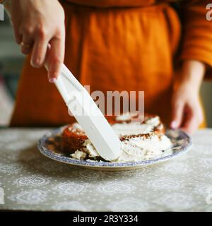 les mains des femmes décorent un gâteau avec de la crème gâteau maison dans la cuisine Banque D'Images