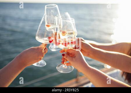 Coucher de soleil sur le ciel et la mer en arrière-plan. Faire un toast de fête avec du vin mousseux Banque D'Images