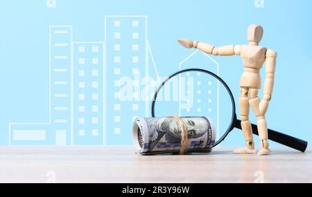 Paquet de dollars en papier, loupe et poupée en bois marionnette sur fond bleu, concept de la hausse des prix immobiliers, h Banque D'Images