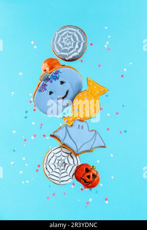 Biscuits de pain d'épice peints pour Halloween avec des saupoudrés sur fond bleu. La lévitation. Banque D'Images