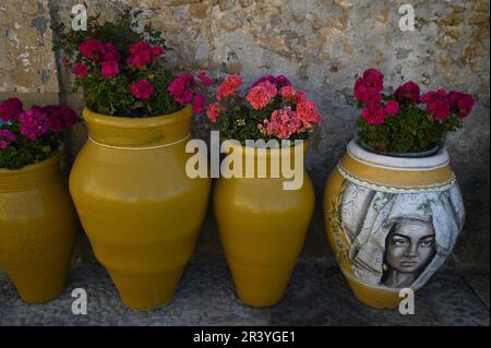 Marzamemi Sicile, Italie, pots d'argile vitrifiée faits à la main avec géraniums sur un mur de pierre fait à la main. Banque D'Images