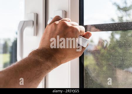 Homme main ouvrant fenêtre en plastique moderne sur une journée ensoleillée, photo de gros plan avec sele ctive soft focus Banque D'Images