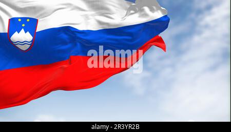 Drapeau national de Slovénie agitant dans le vent par temps clair. Trois bandes horizontales égales de blanc, bleu et rouge, avec des armoiries dans le palan supérieur. Banque D'Images