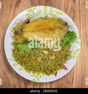 Poulet farci au riz, et servi dans un plat de gruaux cuits aux amandes, sur la table à manger. Banque D'Images