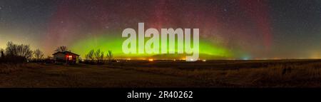 Panorama d'un arc auroral dans le sud de l'Alberta, au Canada, avec la voie lactée plus basse à travers les parallèles nord de l'aurore. Banque D'Images