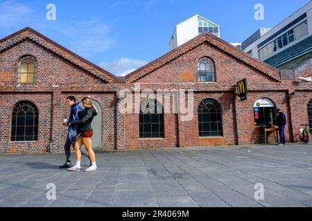 Sandnes, Rogaland, Norvège, May18 2023 ans, Jeune couple marchant dans le centre-ville de Sandnes en soirée sous un ciel bleu passant par le magasin McDonalds Hamburger Banque D'Images