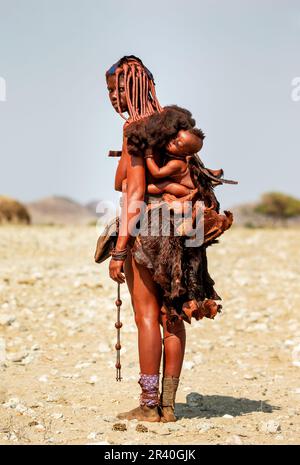 Enfant de la tribu Himba derrière sa mère. Banque D'Images