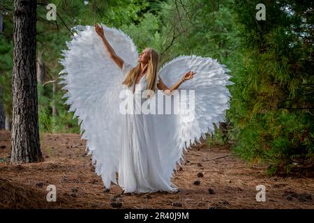 Un joli modèle Blonde pose à l'extérieur tout en portant des ailes blanches faites à la main pour Halloween Banque D'Images