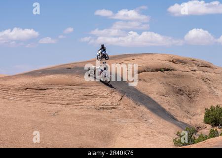 Moto tout-terrain grimpant sur un dôme en grès escarpé de la piste fins & Things, près de Moab, Utah. Banque D'Images