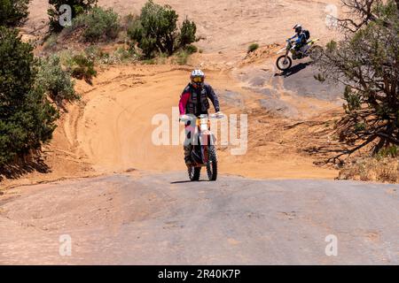 Moto hors route grimpant sur un dôme en grès de la piste fins & Things, près de Moab, Utah. Banque D'Images