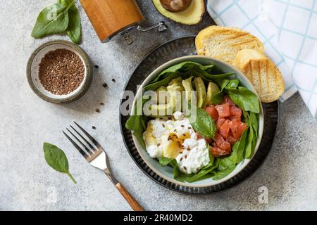 Petit-déjeuner classique, brunch - avec œufs pochés, avocat, arugula, graines de lin et saumon salé sur fond gris. Vue de abo Banque D'Images