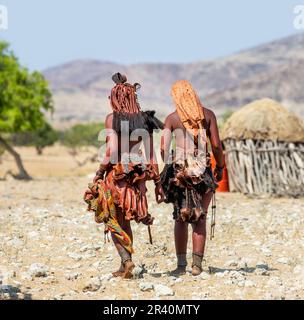 Deux femmes de la tribu Himba marchent dans le désert en vêtements nationaux. Banque D'Images