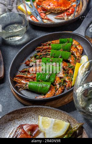 Crevettes tigrées à l'ail épicées crevettes crevettes crevettes sur une poêle à frire avec feuilles de citron sur une table noire en gros plan Banque D'Images